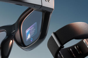 Close-up of smart AR glasses with a digital display showing travel information about Santorini, alongside a sleek black wearable band, both set against a gradient blue background